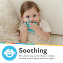 Infant holds a blue and aqua flower-shaped silicone teething toy, designed to soothe sore gums.