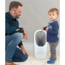 A toddler stands next to a Nuby My Real Urinal Training Toilet while an adult kneels beside him, encouraging use.