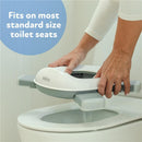 Nuby portable potty seat being placed on a standard toilet, featuring a white design with blue accents.