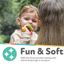 A toddler chewing on a multi-textured, soft silicone Nuby Pasta Ring Teether, looking at a woman nearby.