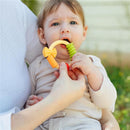 Baby holding a multi-textured Nuby Pasta Ring Teether made of soft silicone, being assisted by an adult.