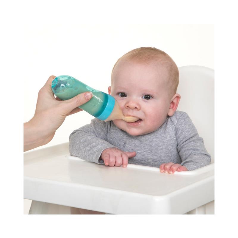 Nuby Silicone Squeeze Feeder in use, with an adult hand feeding a baby sitting in a high chair.