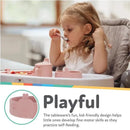 Silicone whale-shaped baby feeding bowl in pink blush, with a young child using a spoon to eat from it.
