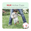 Child playing with a soccer ball in a garden, while an adult stands nearby, promoting NUK Active Cups for easy bottle-to-cup transition.