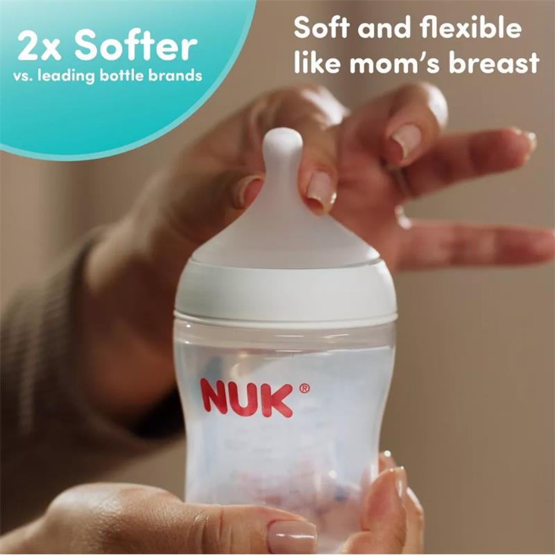 Nuk 5 oz baby bottle, held in a hand, featuring a soft, flexible nipple, promoting comfort similar to breastfeeding.