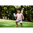 Smiling child holding a light blue Nuk sippy cup, running on grass in sunny outdoor setting.