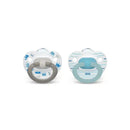 Two Nuk fashion pacifiers, one with a gray handle and royal-themed design, the other with a turquoise handle and striped pattern.
