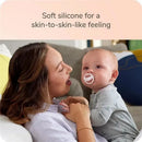 Soft silicone pacifier held by a baby, with text highlighting a skin-to-skin-like feeling.