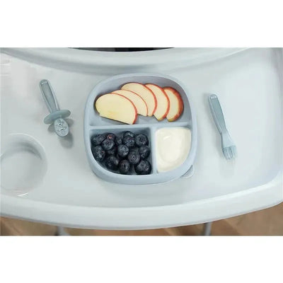 Blue NUK suction plate with apple slices, blueberries, and yogurt, accompanied by a matching spoon and fork on a high chair tray.