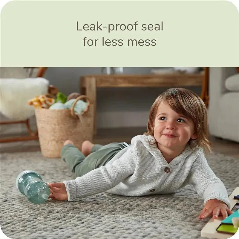 NUK Nature Everlast Weighted Straw Cup beside a smiling young child on a carpet, emphasizing a leak-proof design.