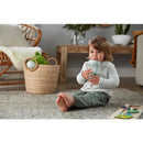 Child sitting on a rug, holding a NUK Nature Everlast Weighted Straw Cup, barefoot, in a cozy living room setting.