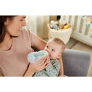 Mother feeding a baby with a Nuk Smooth Flow Pro Anti-Colic Baby Bottle in a cozy indoor setting.