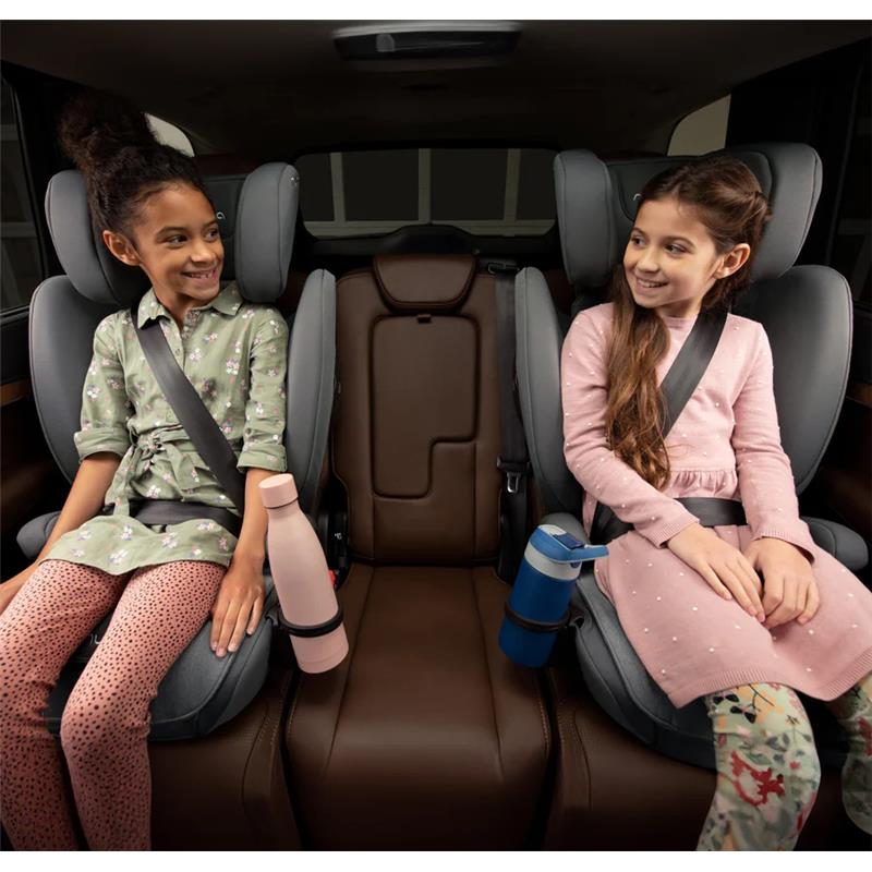 Two young girls sit in a car, each in a Nuna AACE Booster Seat - Caviar, smiling and secured with seat belts.
