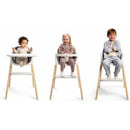 Nuna BRYN High Chair in Sanderson with two toddlers and a young child seated, smiling, showcasing its comfort and design.