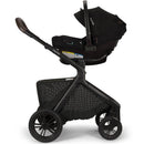Nuna DEMI™ icon Stroller in Caviar, showcasing a sleek black design with a car seat attached and a mesh storage basket below.