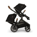 Nuna DEMI next Sibling Seat in Caviar, featuring two adjustable canopies, a sleek black design, and modern wheels.
