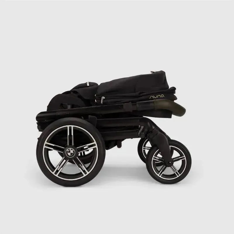 Nuna MIXX™ next stroller in black, featuring a magnetic buckle and sleek design, shown in a folded position.
