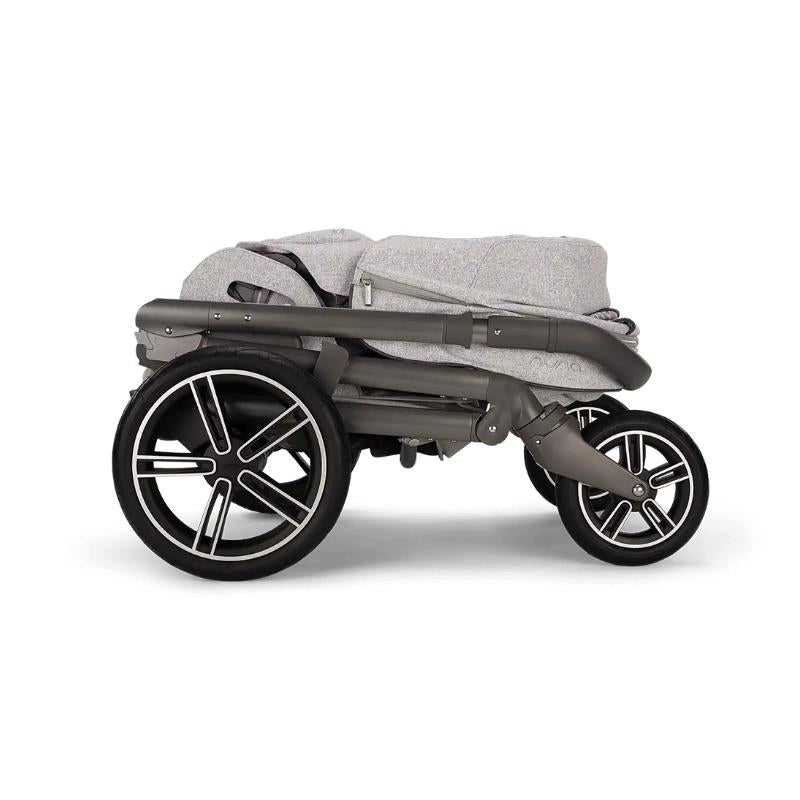Nuna MIXX™ next Stroller in Sterling color, shown in a folded position with sleek black wheels and grey fabric.