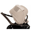 Nuna MIXX™ next stroller in Biscotti color, featuring a soft, textured bassinet and leatherette handlebar.