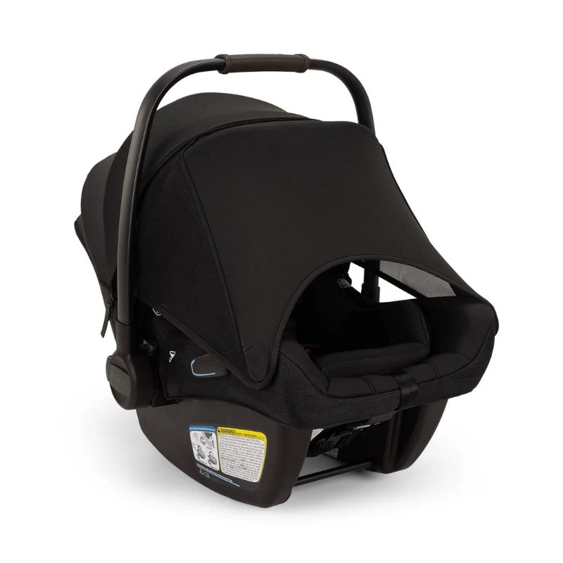 Nuna Pipa Aire Rx infant car seat in caviar/chocolate color, featuring a sun canopy and safety labels on the side.