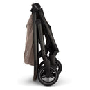 Nuna Swiv + Pipa Aire Rx Travel System in Cedar, displayed in a folded position showing its sleek design and wheels.