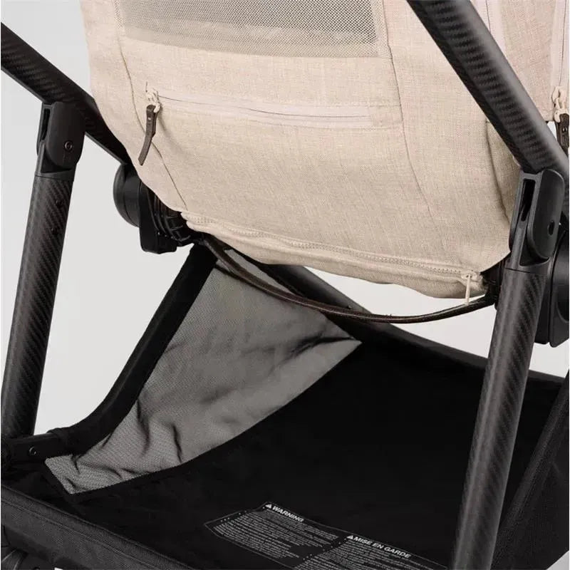 Nuna SWIV™ Stroller - Biscotti showing the undercarriage, featuring a mesh storage area and care instructions label.