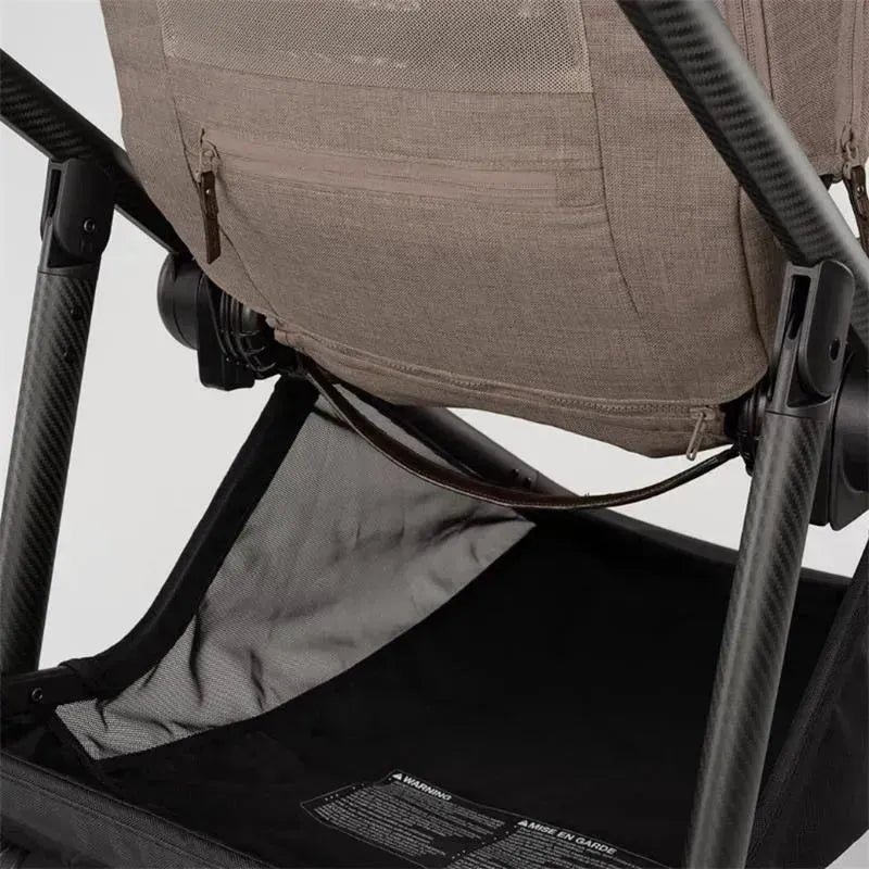 Nuna SWIV™ Stroller in Cedar color, showcasing a close-up of the mesh backrest and storage basket with warning label.