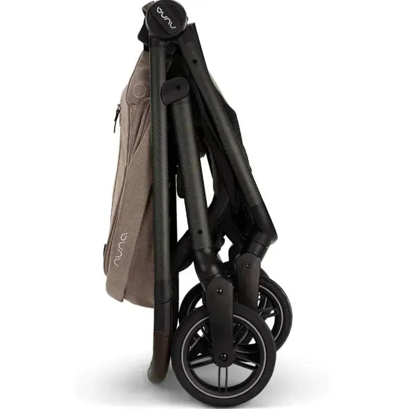 Nuna SWIV™ Stroller in Cedar color, shown in a folded position with a sleek design and compact wheels.