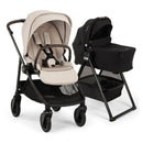 Nuna Swiv stroller with a beige seat and black frame next to a black Swiv bassinet on a stand, designed for infants.