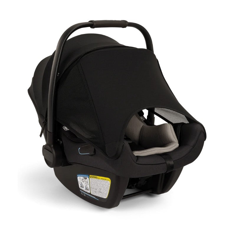 Nuna Pipa Aire infant car seat in Caviar, featuring a protective canopy, safety harness, and visible instructions on the base.