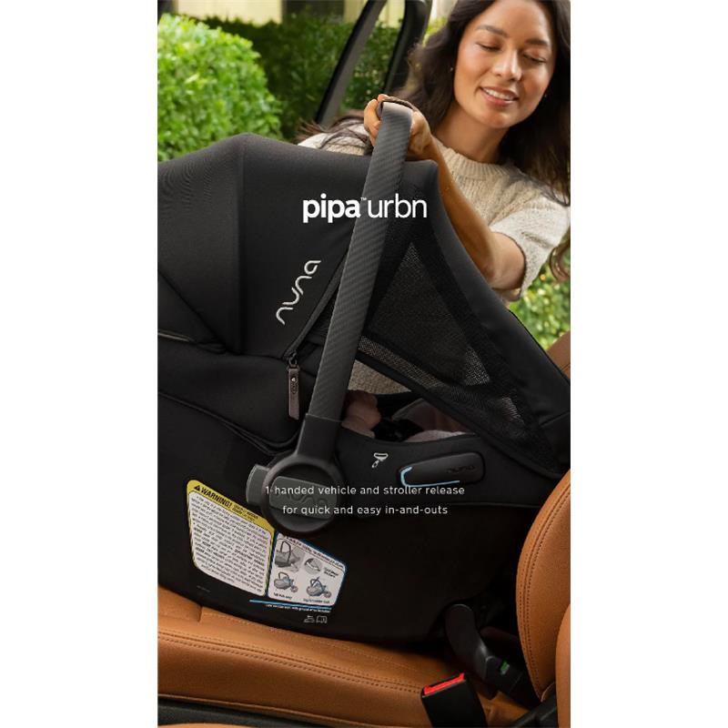 Nuna Pipa Urbn car seat being held by a woman, showcasing its black fabric, safety harness, and one-handed release feature.
