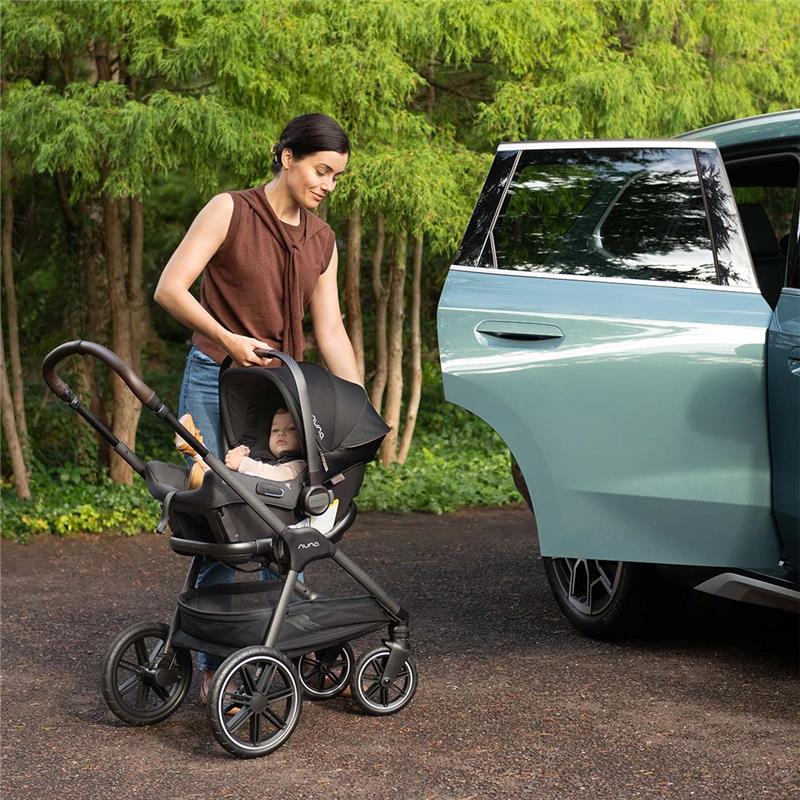Mom using the Nuna Triv Lx travel system with a Pipa Urbn infant seat, assisting a child next to a vehicle.