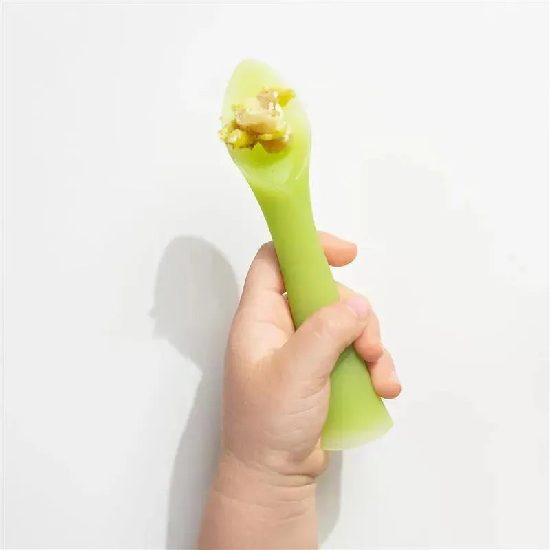 Soft-tip green silicone training spoon held by a small hand, with food on the tip, ideal for baby-led weaning.