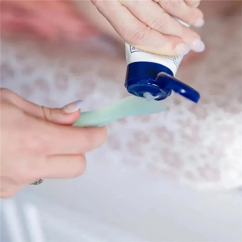 Diaper rash cream applicator with suction base, blue color, dispensing cream onto a green applicator stick.