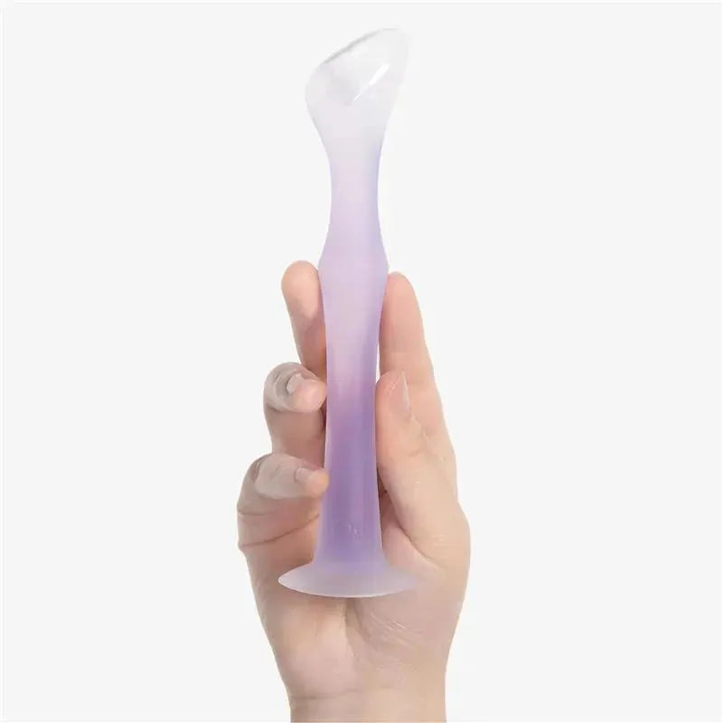 Diaper rash cream applicator by Ola Baby, featuring a suction base and a coral gradient design, held by a hand.