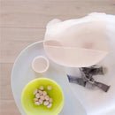Foldable lilac silicone baby bib displayed with a green bowl containing small food items, resting on a high chair tray.