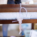 Silicone strap designed to secure items, featuring a transparent base and flexible attachment, hung from a wooden frame.