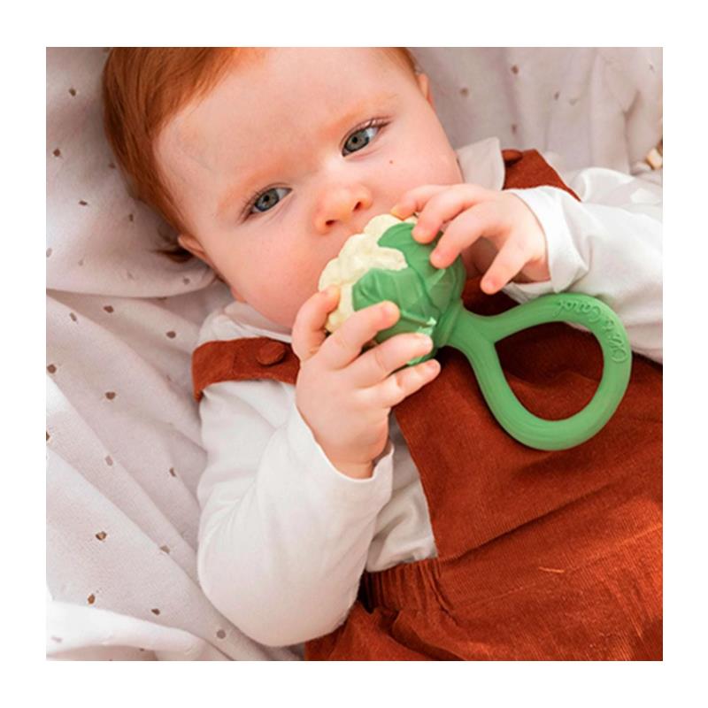 Baby with red hair holding a green and white cauliflower-shaped rattle toy.