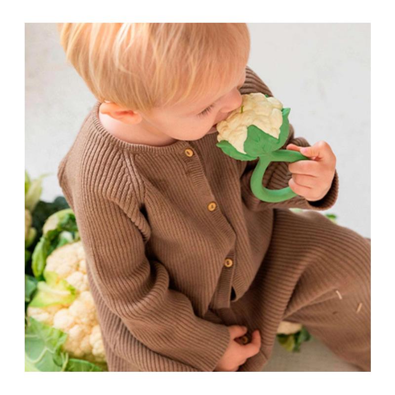 Young child in a brown outfit holds an Oli & Carol cauliflower rattle toy, exploring it with curiosity.