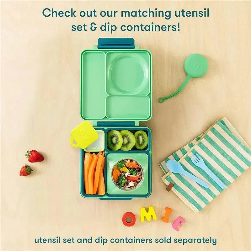 Lime and meadow green OmieBox lunchbox with compartments holding strawberries, carrots, kiwi, and a dip container on a wooden table.