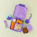 Purple OmieBox food storage container with a lid, featuring compartments filled with carrots, mango, dipping sauce, and pretzels.