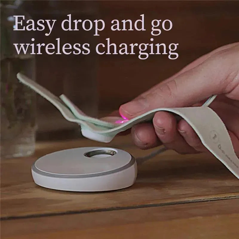 Mint-colored Owlet Dream Sock monitor being placed onto a white circular charging base, with text promoting wireless charging.