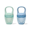 Two silicone self-feeders in opal green and dusk blue colors, designed for toddlers, featuring ergonomic handles and textured grips.