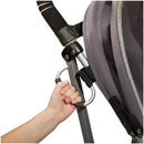 Hand gripping an Oxo grey stroller hook attached to a stroller frame, demonstrating its functionality for carrying items.