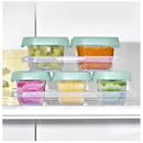 Oxo Tot 12-piece baby food storage container set in opal, featuring colorful fruit purees in stackable containers with green lids.