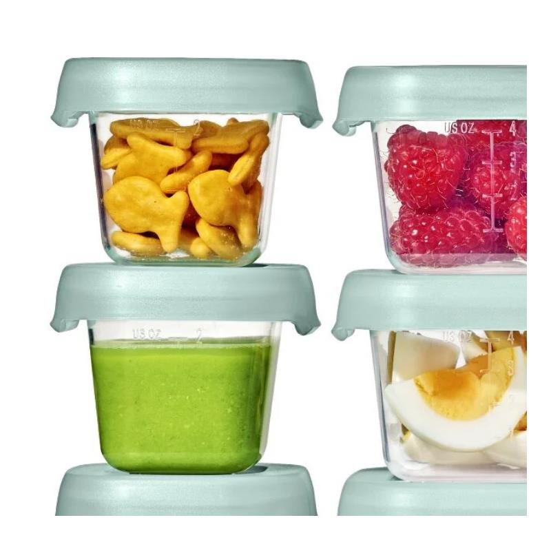 Oxo Tot 12-piece baby food storage container set in opal, featuring clear containers with green lids, holding snacks and baby food.