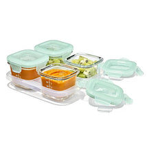 Oxo Tot Glass Baby Blocks food storage containers, 4 oz each, with orange puree and chopped fruit, featuring green lids.
