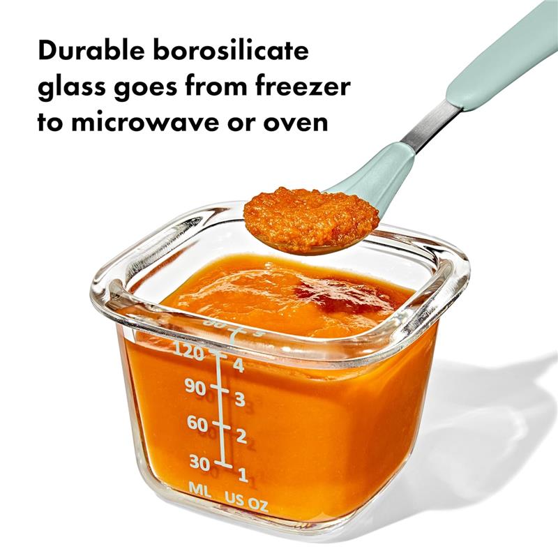 Oxo Tot Glass Baby Blocks food storage container with orange baby food, showcasing measurement markings and a spoon.