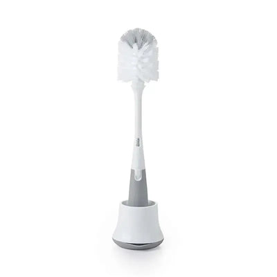 OXO Tot Bottle Brush with a white bristle cleaner, placed upright in a gray and white stand.