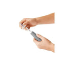 Hands holding the OXO Tot Bottle Brush with a gray handle, demonstrating its bristle cleaner and stand features.